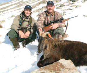 Two hunters and a dead Tahr pose for a photograph