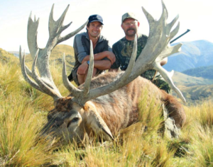 Two hunters and a dead New Zealand Red Stag pose for a picture