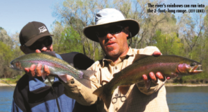 two men, one holding two rainbow trout.