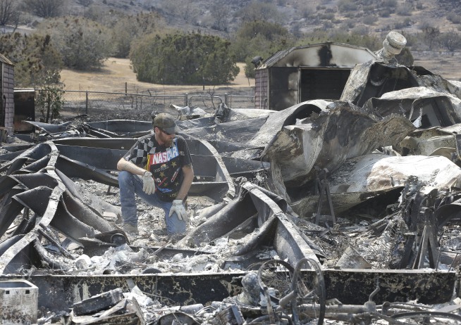 Lucas Martin stares at all that remains of his fire ravaged home in South Lake, Calif., Sunday, June 26, 2016. Martin's home was among the more than 200 homes and buildings destroyed by the fire that swept through the area near Lake Isabella, Calif. (AP Photo/Rich Pedroncelli)